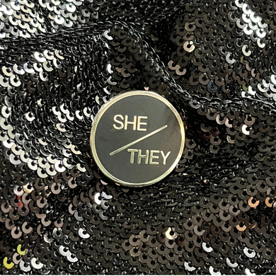 She/They pronoun pin from Queen On The Scene.