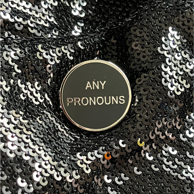 Any pronoun pins from Queen On The Scene features a sleek, round pin with the words 'Any Pronouns' on it. Perfect for upscale events, outings, and more. 