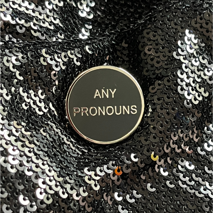 Any pronoun pins from Queen On The Scene features a sleek, round pin with the words 'Any Pronouns' on it. Perfect for upscale events, outings, and more. 
