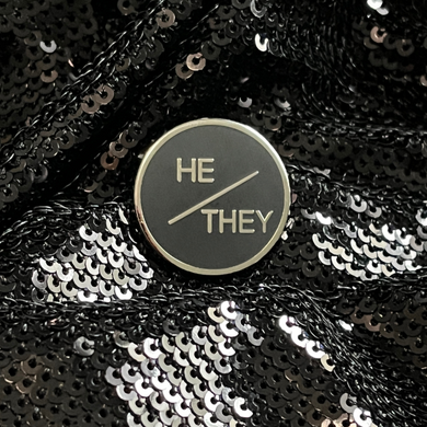 He/they pronoun pin from Queen On The Scene. Sleek, round, professional pronoun pin. 