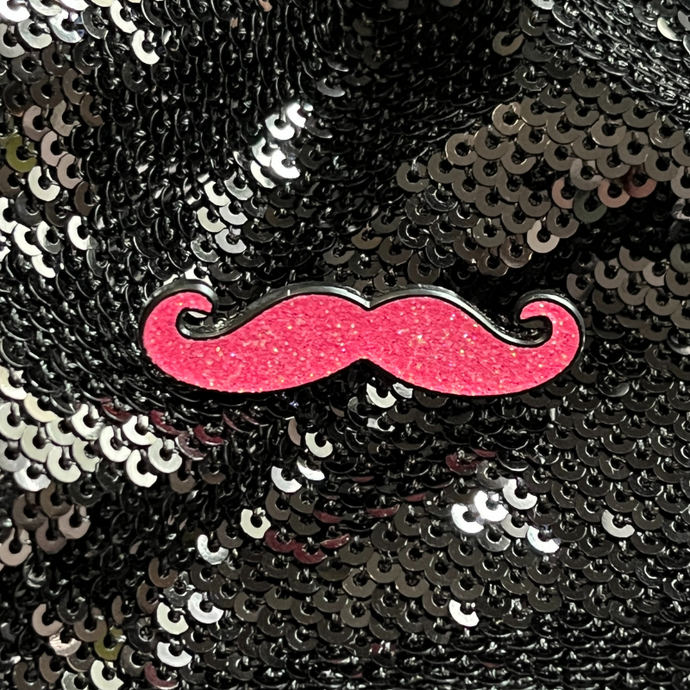 Pink mustache enamel pin by Queen On The Scene. Pink glitter and in the shape of a mustache.